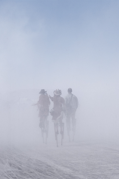 People on stilts during a dust storm