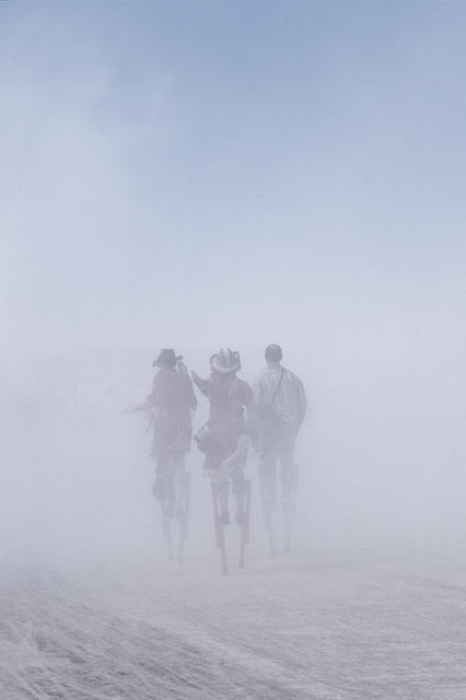 People on stilts during a dust storm
